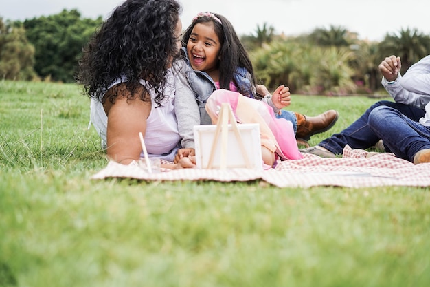 Happy indian family having fun painting with children outdoor at city park  Main focus on female kid face