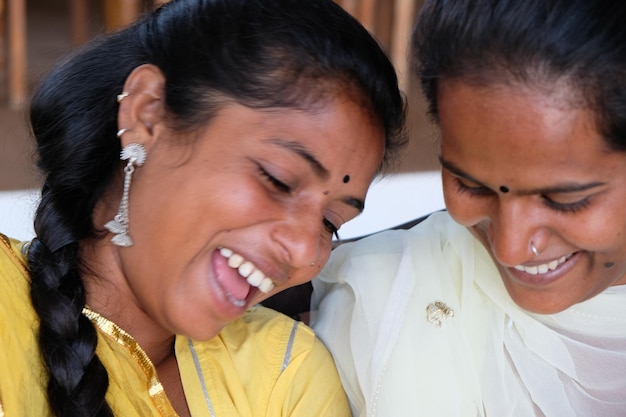 Happy Indian female friends enjoying their time in a cafe smiling and looking down on something