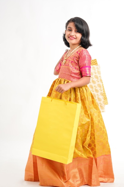 Happy Indian little girl holding shopping bags on white background