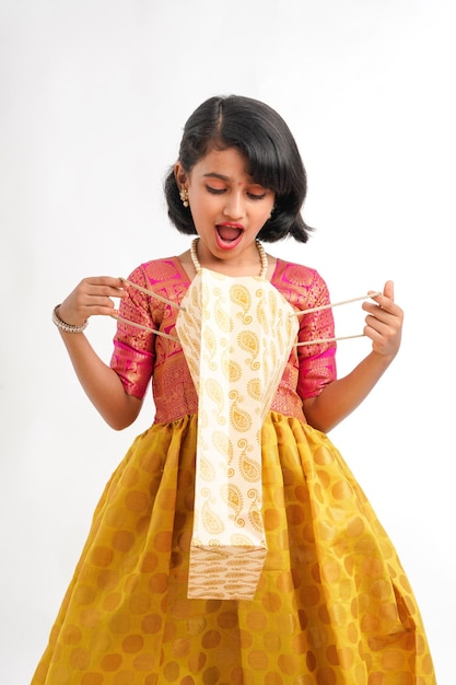 Happy Indian little girl holding shopping bags on white background