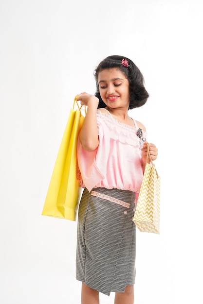 Happy Indian little girl holding shopping bags on white background