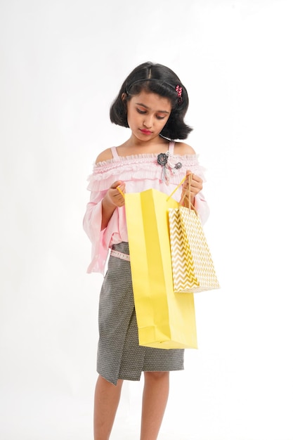 Happy Indian little girl holding shopping bags on white background