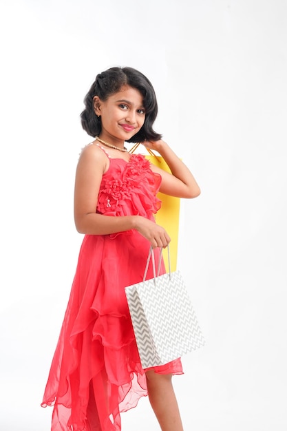 Happy Indian little girl holding shopping bags on white background