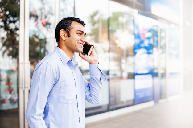 Happy Indian man talking on phone outside the office