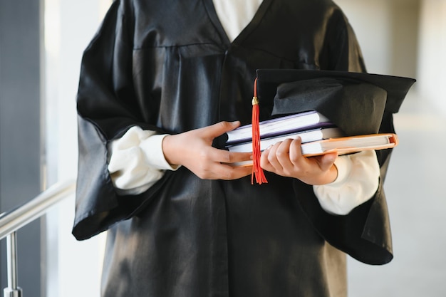 Happy Indian university student in graduation gown and cap holding diploma certificate.