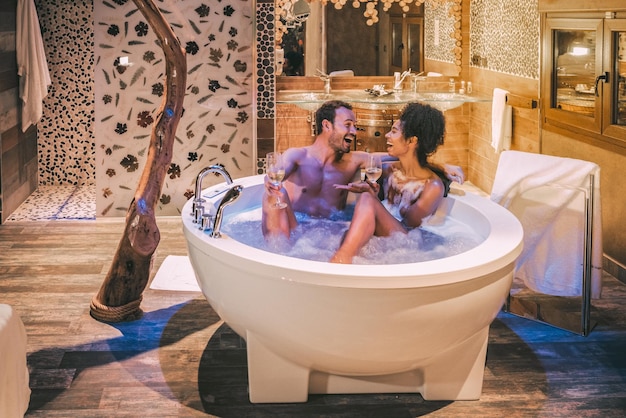 Happy interracial couple relaxed in the jacuzzi enjoying their self and drinking wine xA