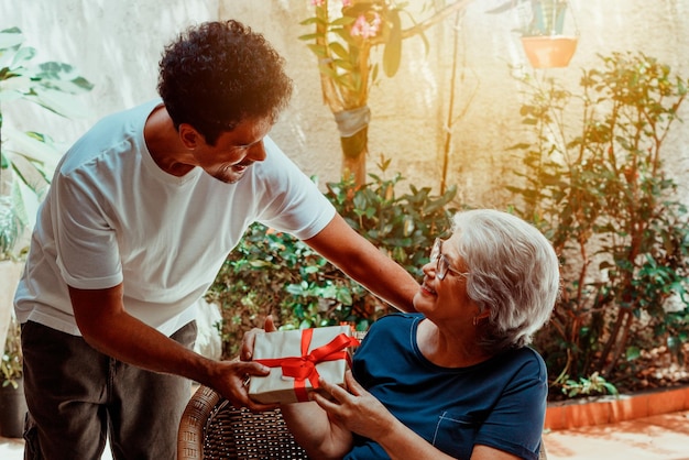 Happy interracial family Son gives a gift to his mother in the house garden Caucasian mother and her black son photo