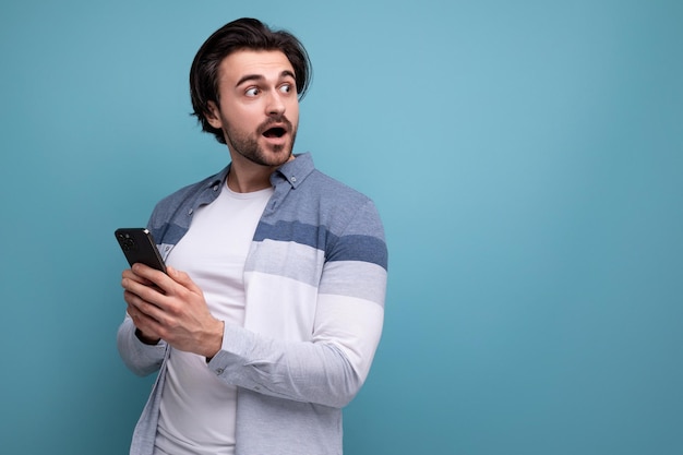 Happy joyful brunette guy in casual style with a smartphone in his hands