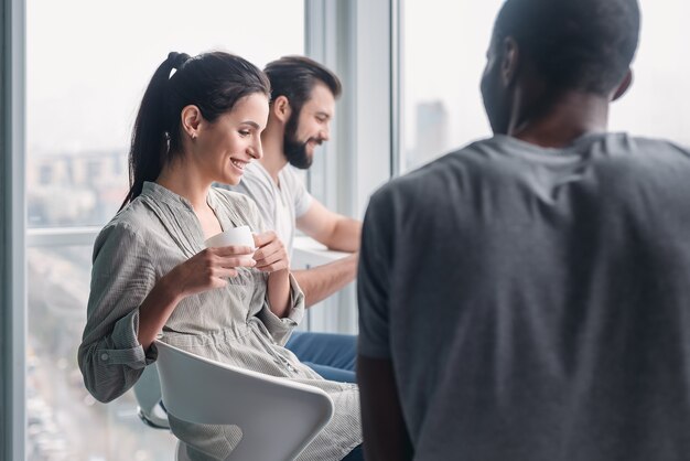 Happy joyful diverse business people laughing at funny joke talking at work break, cheerful corporate team office workers multi-ethnic young coworkers having fun, engaged in teambuilding activity