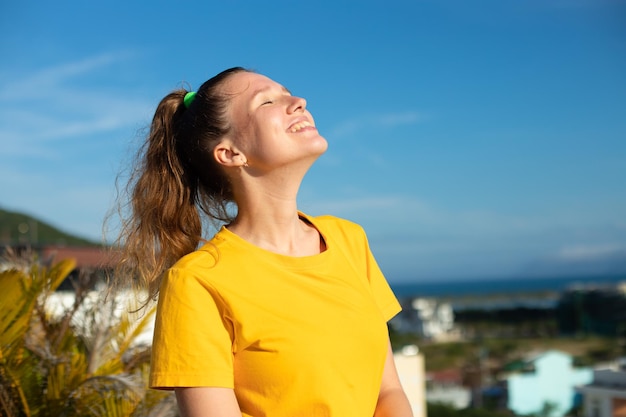 Happy joyful positive girl young beautiful feeling carefree woman is enjoying vacation at summer sunny day sunbathing tanning and smiling Happiness freedom concept on sky natural background