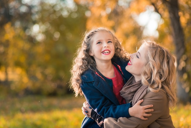 Happy joyful woman having fun with her girl in autumn color