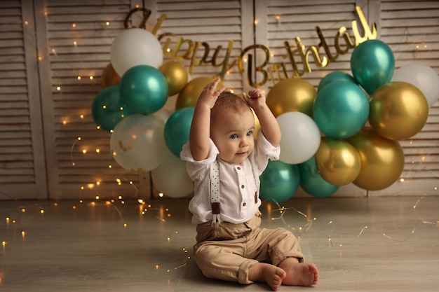 A happy kid on the background of balloons with garlands celebrates his birthday