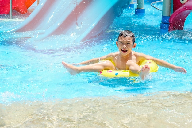 Happy kid boy on safety ring in swimming pool