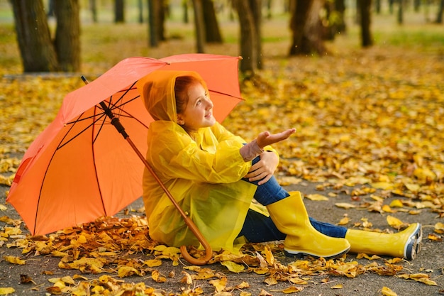 Happy kid catching rain drops in Autumn park