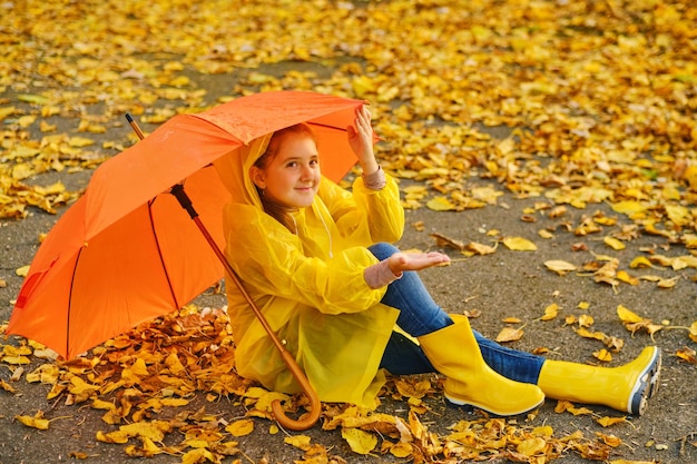 Happy kid catching rain drops in Autumn park