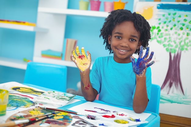 Happy kid enjoying painting with his hands