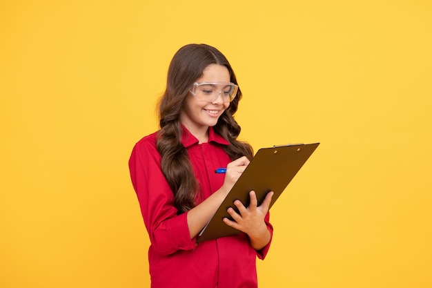 Happy kid girl in eyeglasses hold paper folder noting