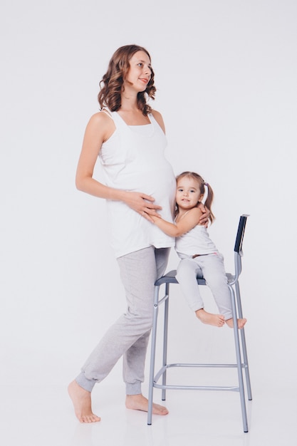 Happy kid girl hugging pregnant mother's belly, pregnancy and new life concept