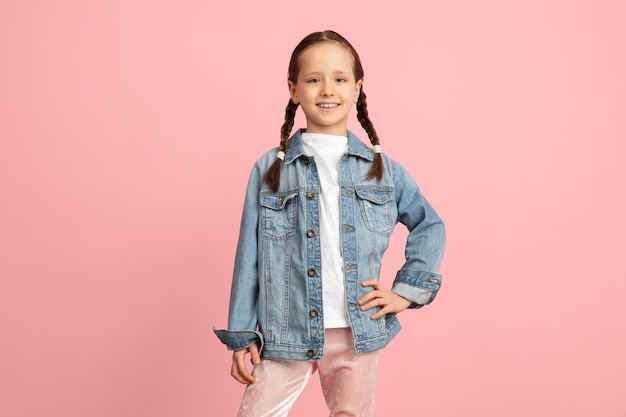 Happy kid girl isolated on pink studio background Looks happy cheerful sincere Copyspace Childhood education emotions concept