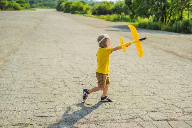 Happy kid playing with toy airplane against old runway background Traveling with kids concept