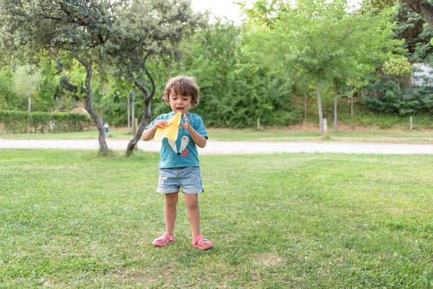 Happy kid playing with toy airplane against summer sky background at sunset