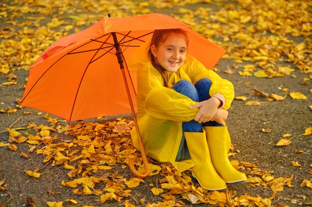 Happy kid Sits in the autumn park