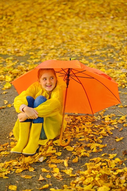 Happy kid Sits in the autumn park