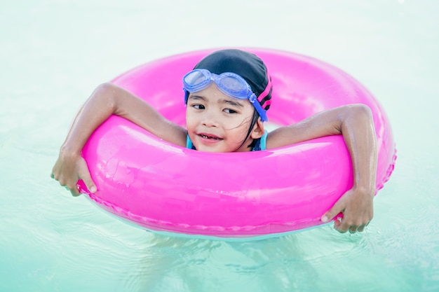 Happy kid swimming in safety ring rubber in pool