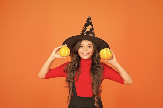 Happy kid in witch hat costume to halloween with small yellow pumpkin halloween food