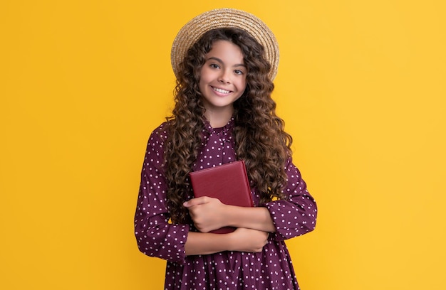 Happy kid with frizz hair hold book on yellow background