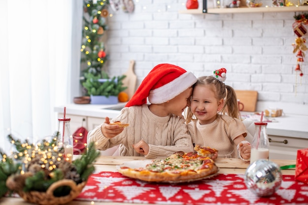 happy kids brother and sister eating pizza in the kitchen