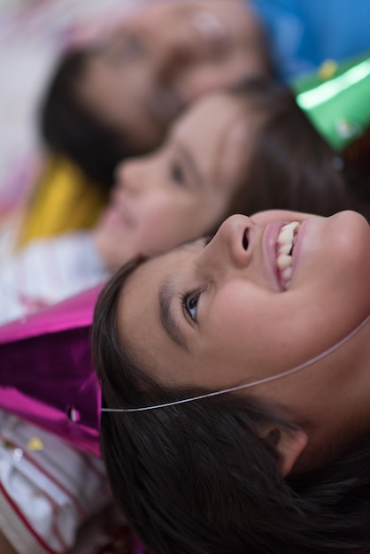 Happy kids celebrating party with blowing confetti while lying on the floor