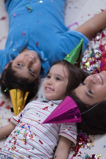 Happy kids celebrating party with blowing confetti while lying on the floor