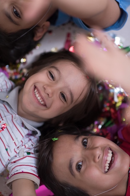 Happy kids celebrating party with blowing confetti while lying on the floor