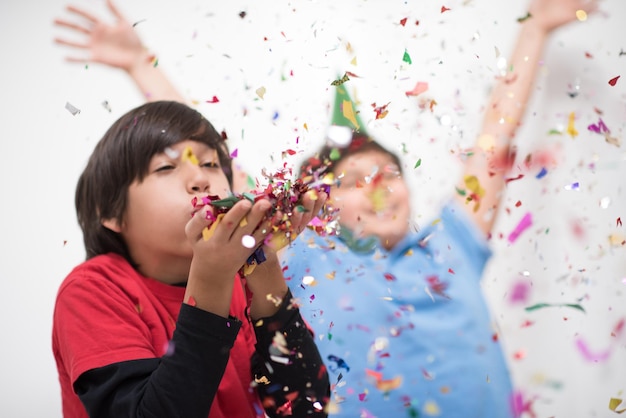 Happy kids celebrating party with blowing confetti