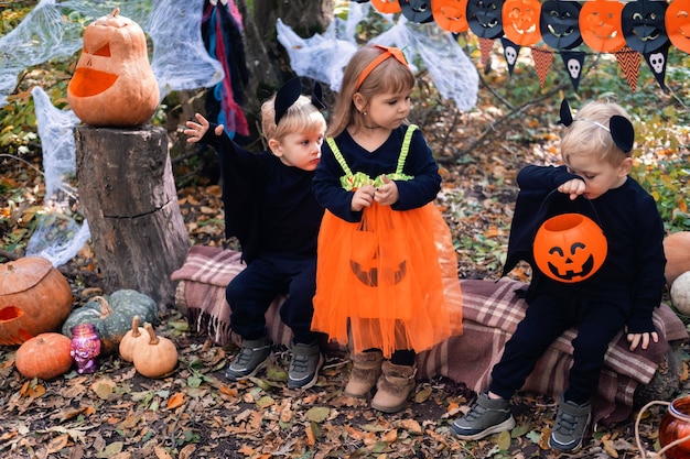 happy kids in halloween costumes having fun in halloween decorations outdoor