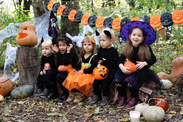 happy kids in halloween costumes having fun in halloween decorations outdoor