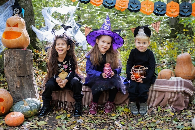 happy kids in halloween costumes having fun in halloween decorations outdoor