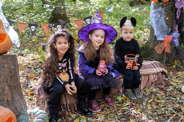 happy kids in halloween costumes having fun in halloween decorations outdoor