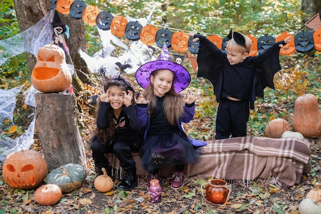 happy kids in halloween costumes having fun in halloween decorations outdoor