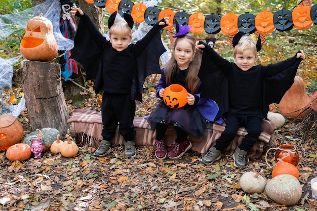 happy kids in halloween costumes having fun in halloween decorations outdoor