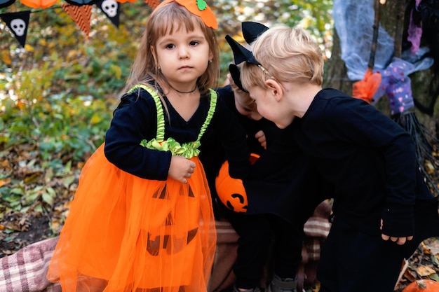 happy kids in halloween costumes having fun in halloween decorations outdoor