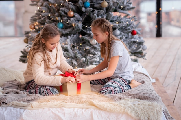 Happy kids having fun and opening presents near christmas tree.