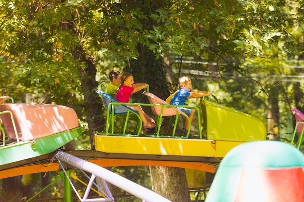 The happy kids on a roller coaster in the amusement park