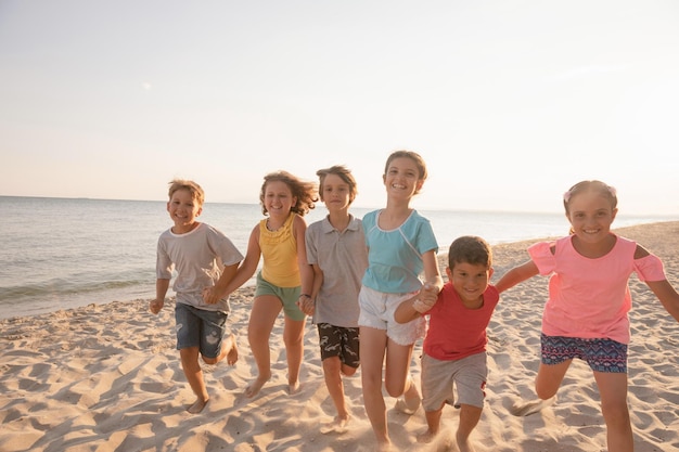 Happy kids running on the beach at sunset Children having fun at summer holidays Smiling boys and girls on vacation on seashore