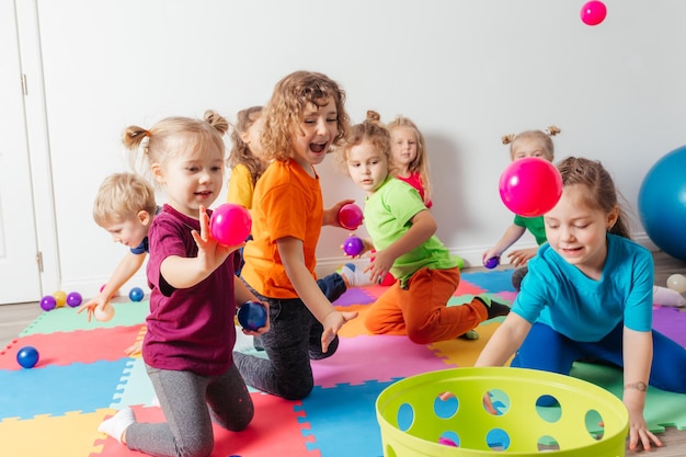 Happy kids throwing balls into plastic basket