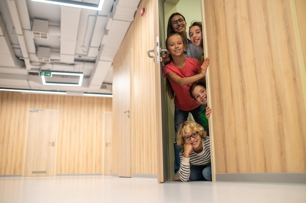 Happy kids with woman opening door looking at camera