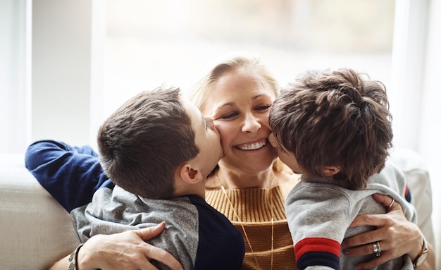 Photo happy kiss and mother with children on sofa for bonding loving relationship and relax together in home family love and mom with young boys embrace for affection care and smile in living room