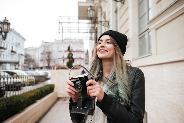 Happy lady walking on the street while holding camera.