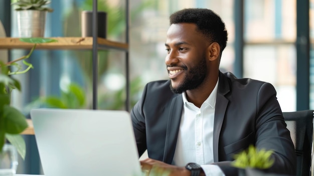 A happy Latin businessman is working on a laptop in a modern office setting